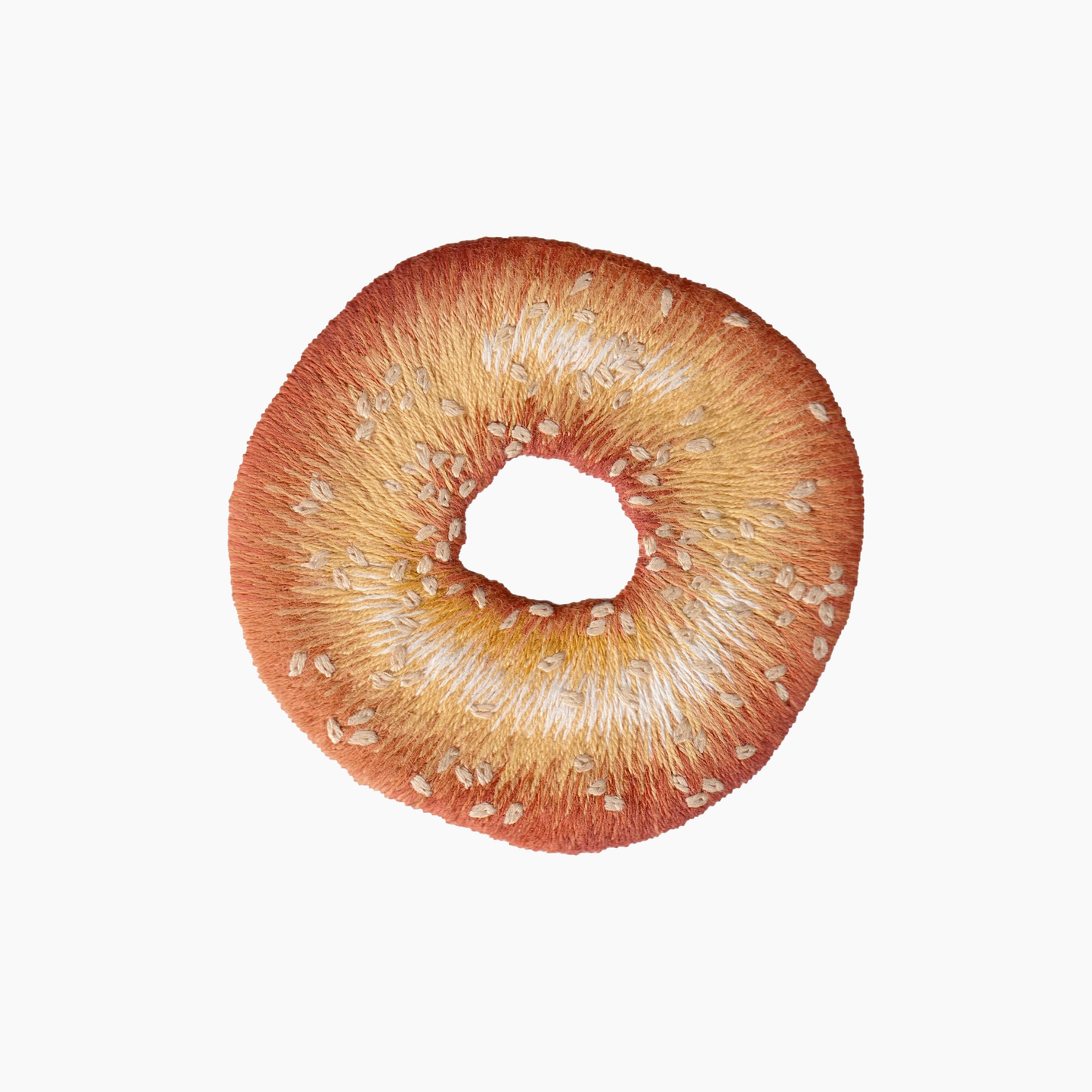 Hand embroidered cotton towel with seeded brown bagel on a white background