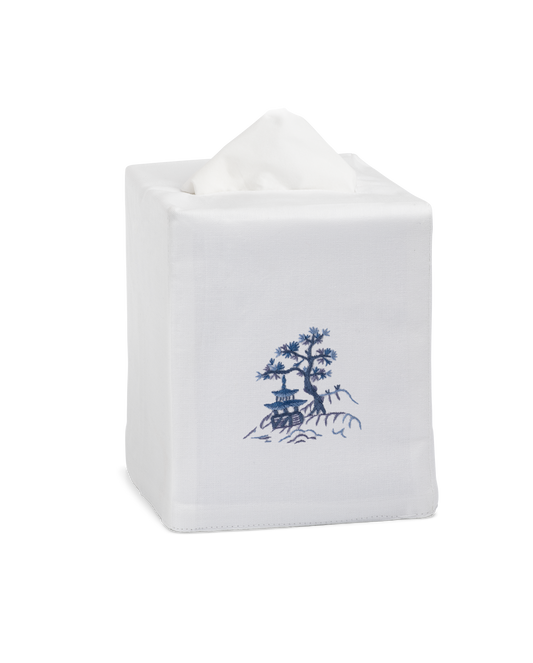 A white tissue box cover with a house & tree on a hill embroidered in blue in the center.
