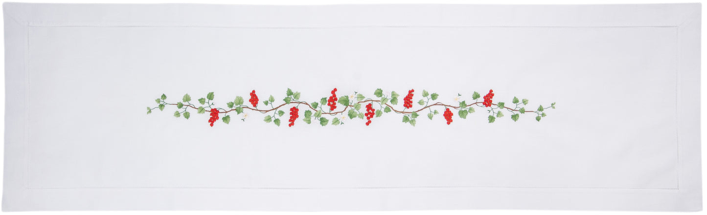 A white table runner with a hemstitch border. A vine of currents is embroidered in a line down the middle.