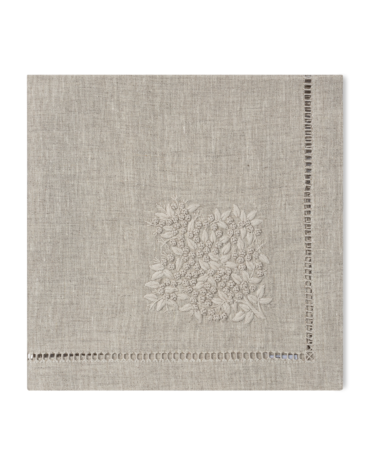 A natural linen napkin with a hemstitch border and natural french knot floral embroidery