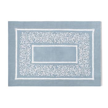 A sky blue linen placemat with a hemstitch border and white french knot floral embroidery
