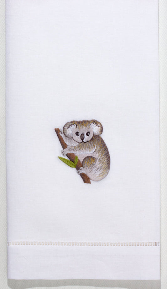 A white hand towel with a hemstitch. A gray koala on a branch is embroidered in the center