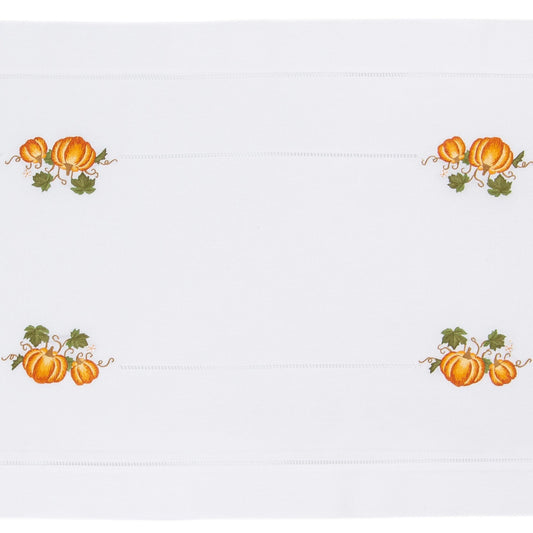A white table runner with a hemstitch border. A border of pumpkins goes around the edge