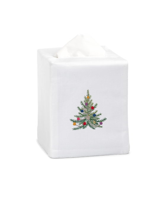 A white tissue cover with a green christmas tree with glittery ornaments in the center.