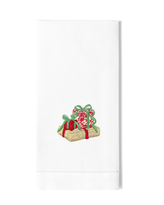 A white hand towel with a hemstitch. A trio of glittering christmas gifts are embroidered in the center