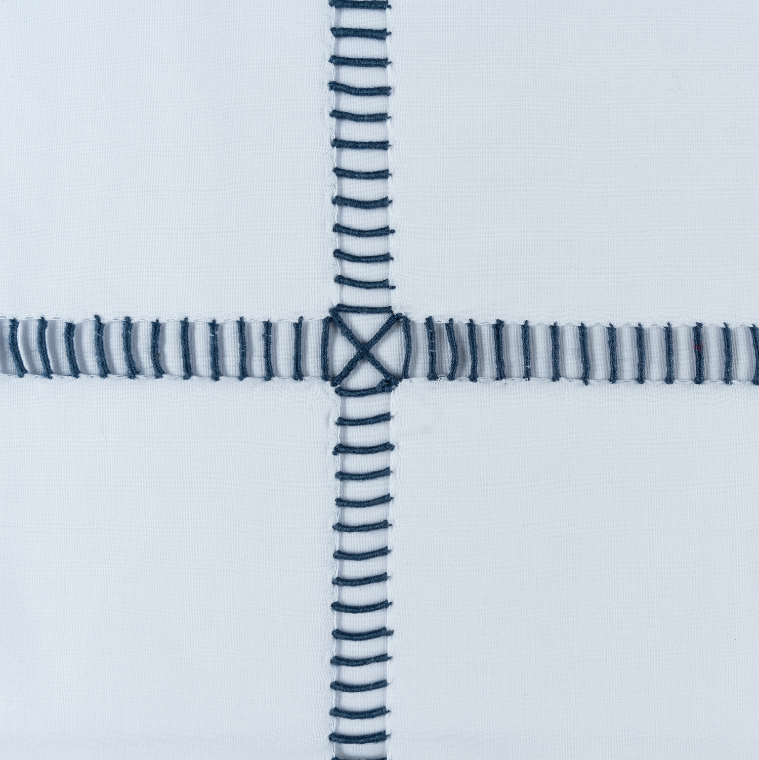 Close-up of a white fabric with blue striped stitching on a light gray background