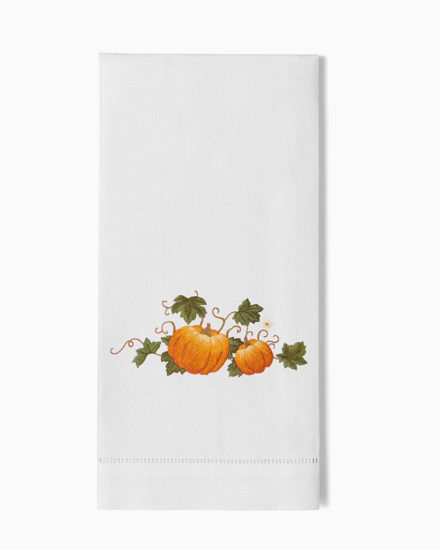 A white Henry Handwork dish towel with Pumpkins Grande Hand Towel and leaves on it.