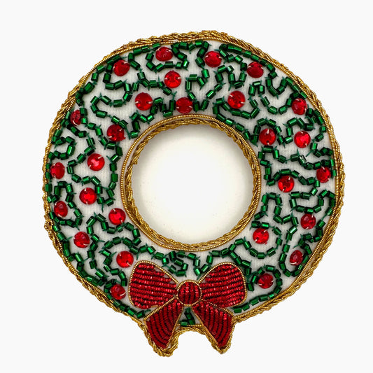 Image of a red berry and snowy wreath Christmas ornament with intricate beadwork. 