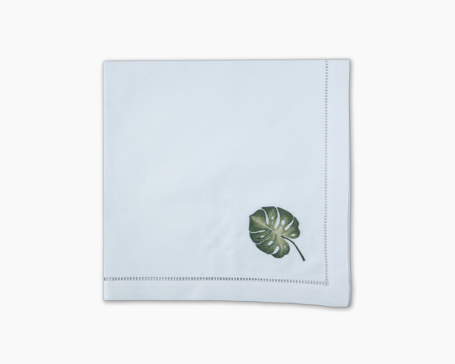 A Tropical Leaf Napkin with a green leaf on it by Henry Handwork.