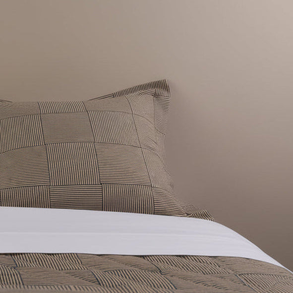 Textured brown pillow and bedding on a neutral background
