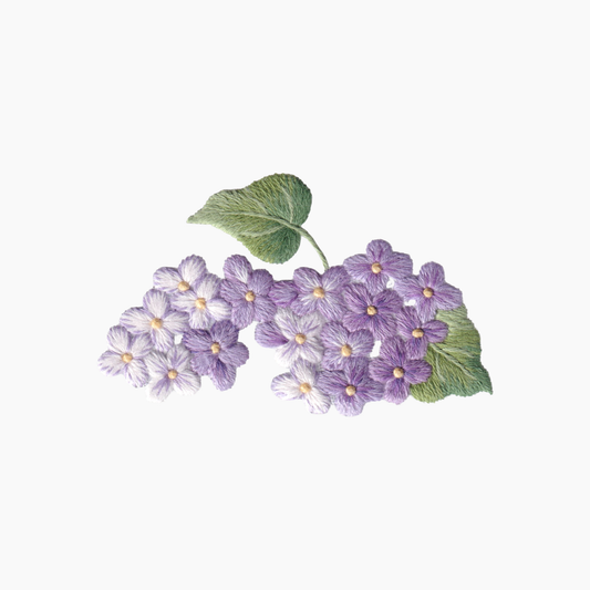 Hand embroidered cotton boutique tissue box cover of arrangement of purple lilac flowers with green leaves on a white background