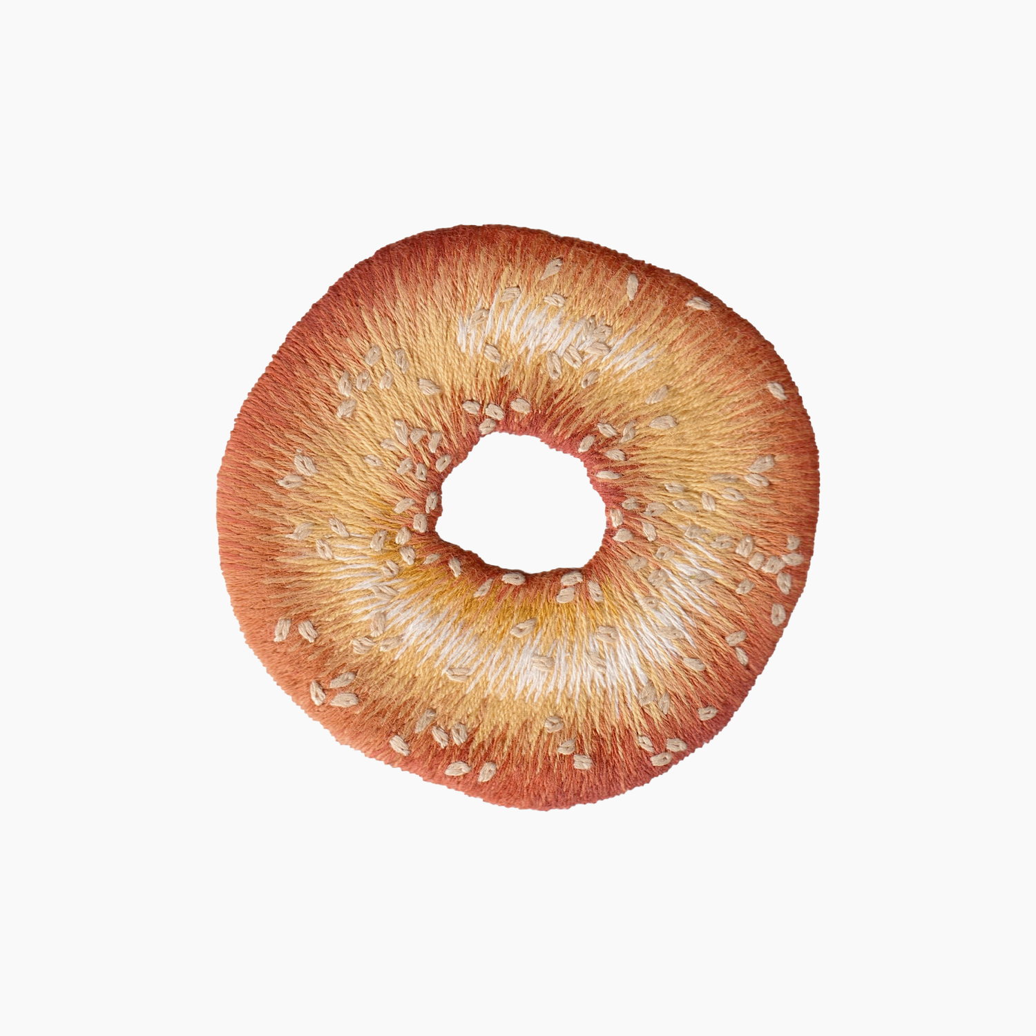 Hand embroidered cotton towel with seeded brown bagel on a white background