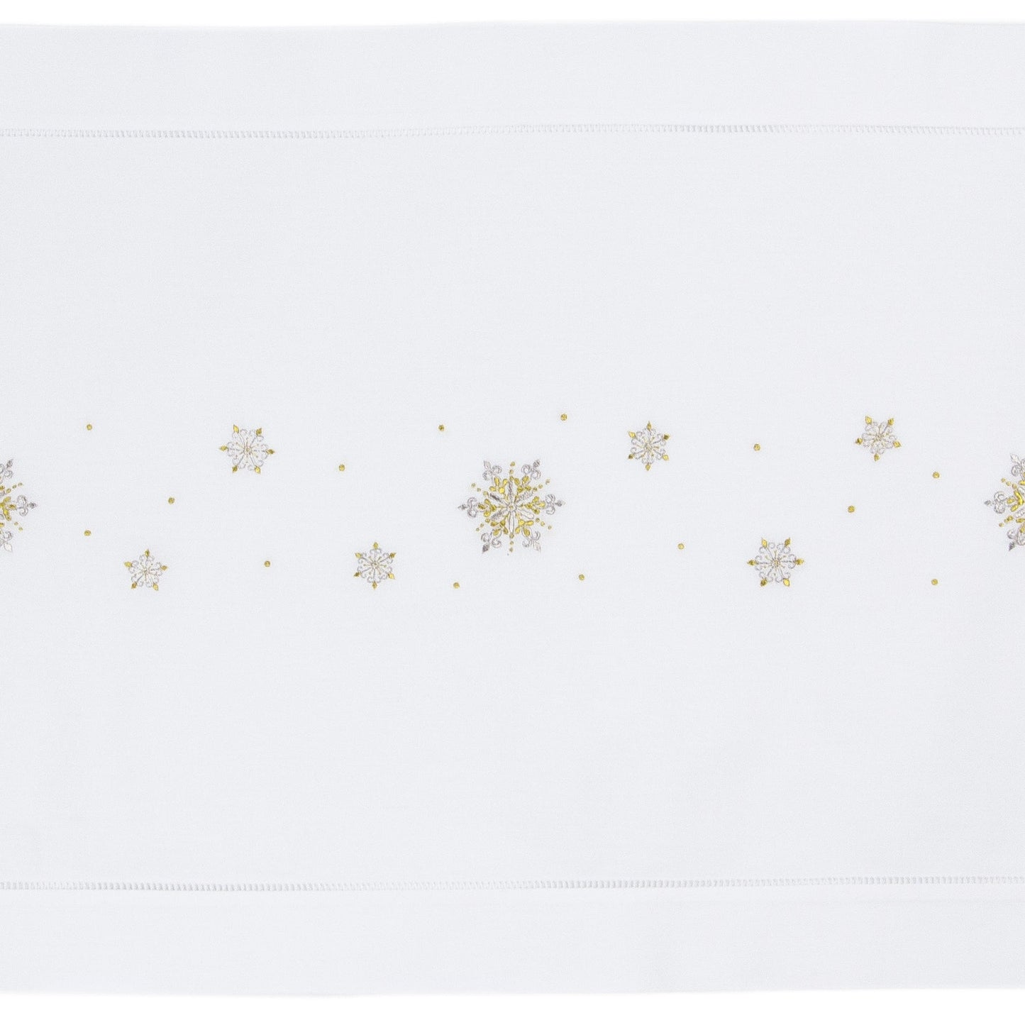 A white table runner with a hemstitch border. Gold & silver metallic snowflakes are embroidered in a line down the middle