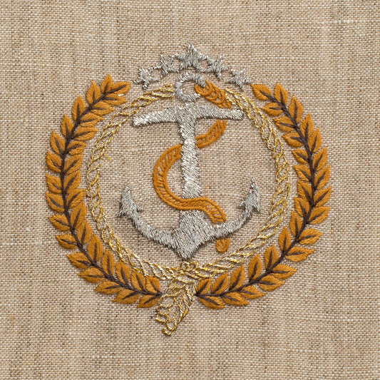 A close up detailed image of the embroidery - a silver anchor with a gold laurel wreath circling it. 5 Silver stars sit above the anchor.