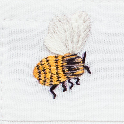 A close up detailed image of the embroidery - a flying black & yellow bumblebee with white wings.