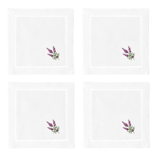 4 white cocktail napkins. Embroidered in the bottom right corner of each is a bundle of lavender