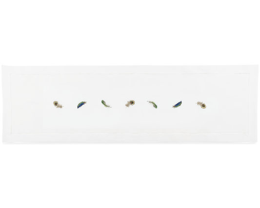 A white runner with a hemstitch border. Embroidered in a line down the center are multiple peacock feathers.