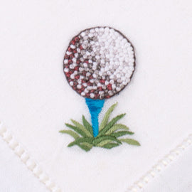 a french knot embroidered golf ball on a blue tee in the grass