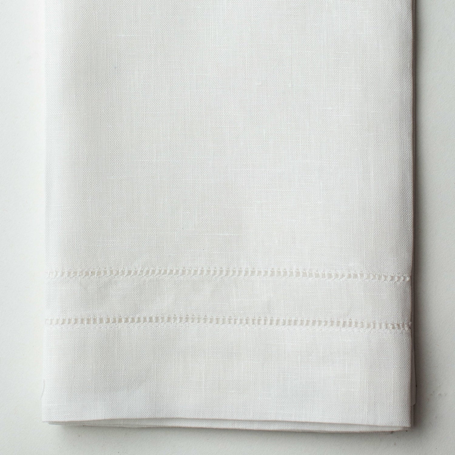 A close up of a white linen hand towel with a hemstitch border