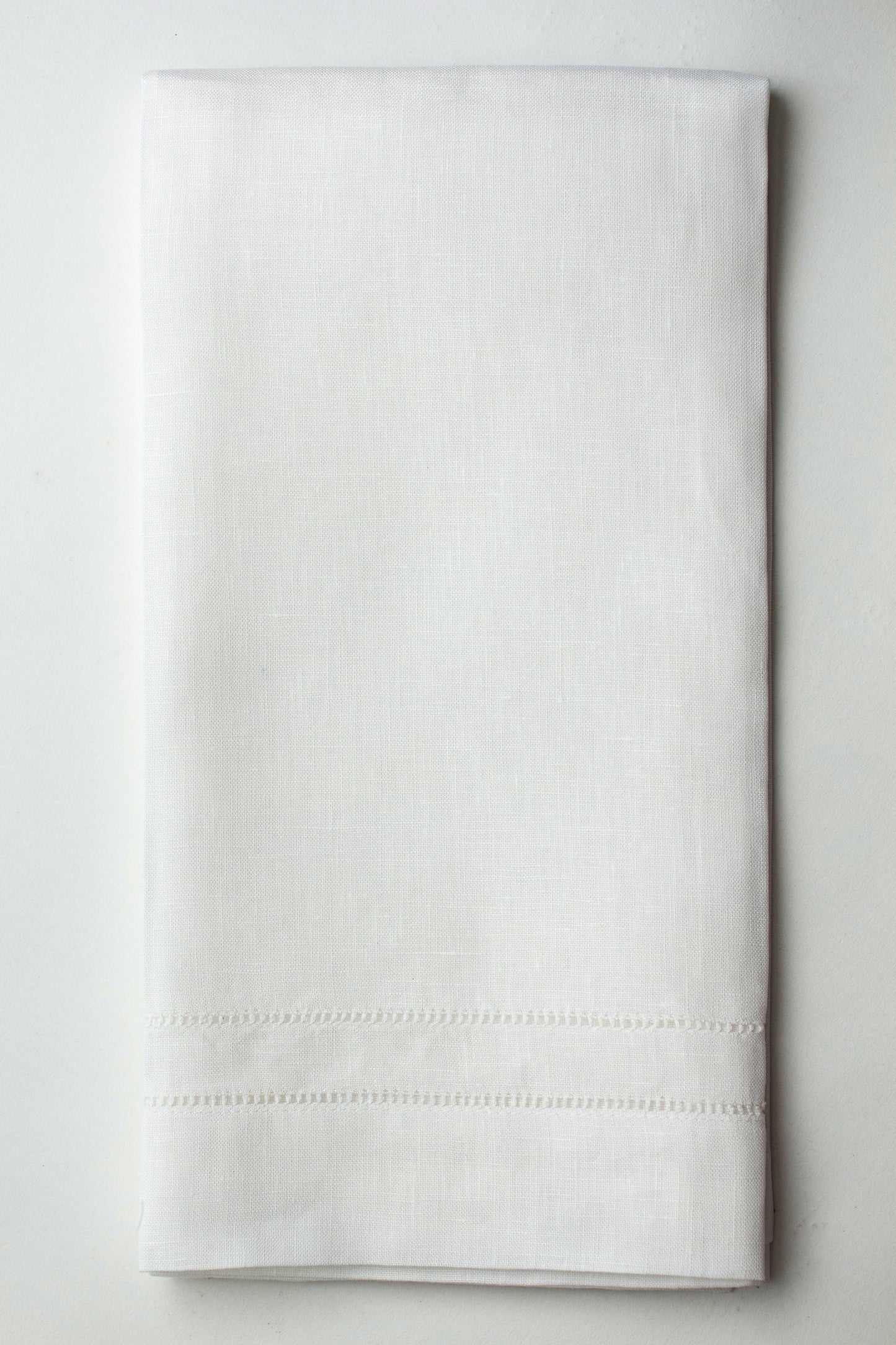 A white linen hand towel with a hemstitch border