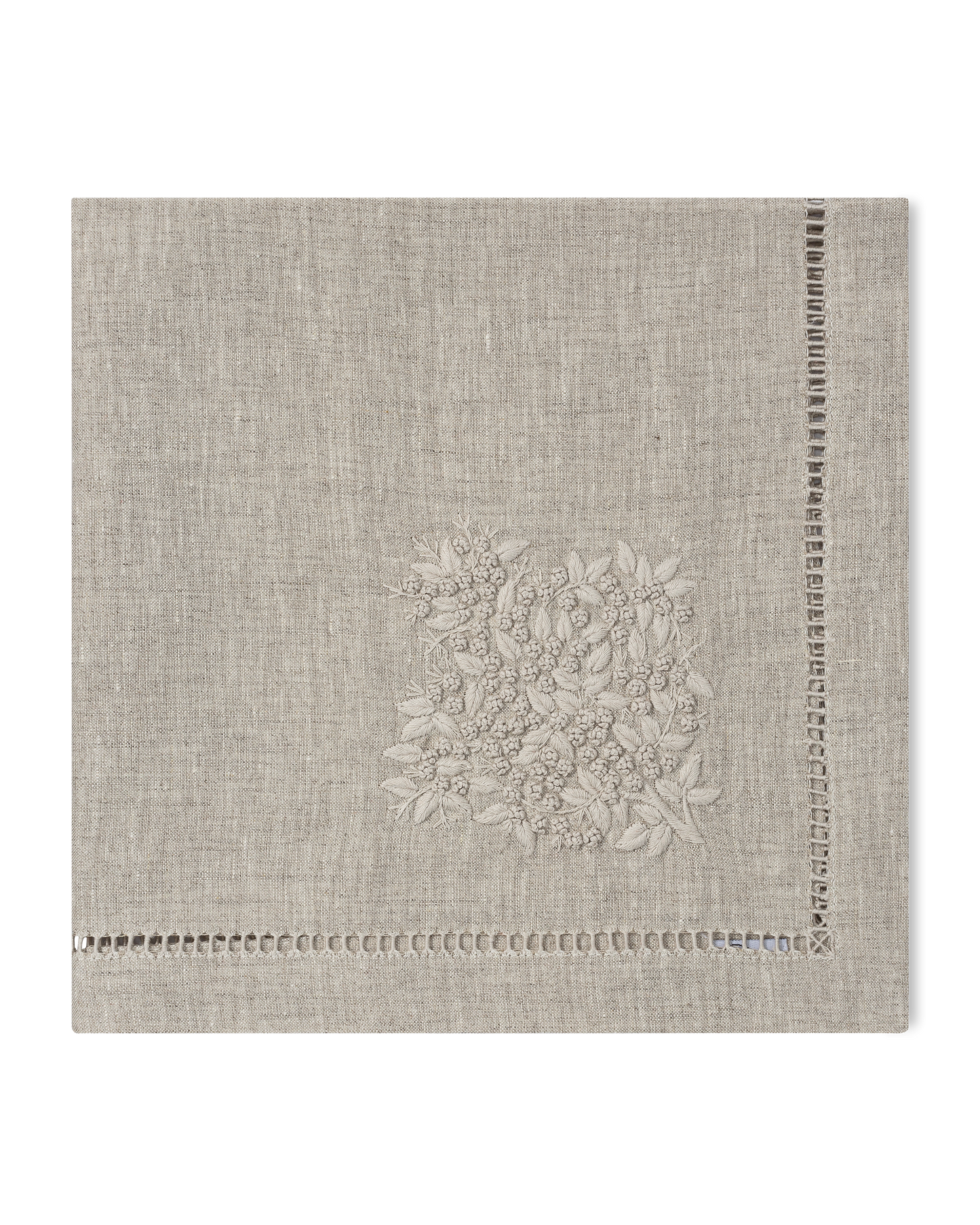 A natural linen napkin with a hemstitch border and natural french knot floral embroidery