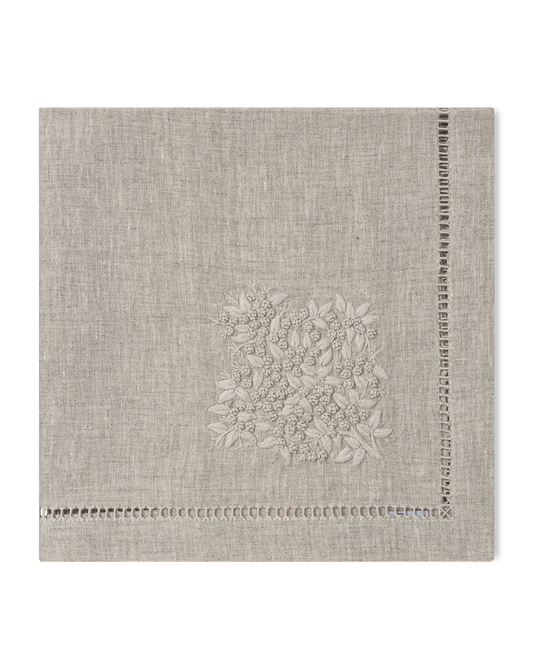 A natural linen napkin with a hemstitch border and natural french knot floral embroidery