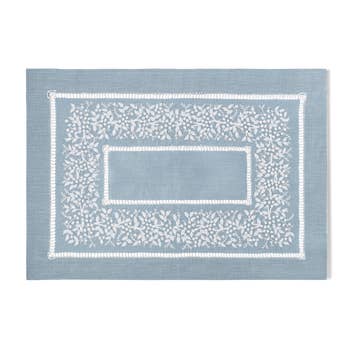 A sky blue linen placemat with a hemstitch border and white french knot floral embroidery
