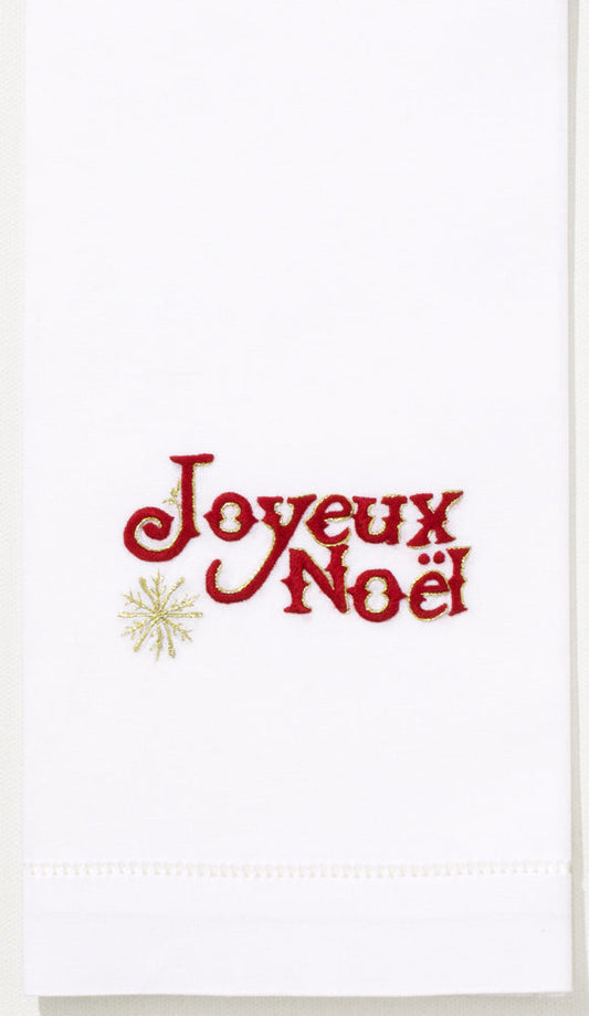 A white hand towel with a hemstitch. Red text saying “Joyeux Noel” is embroidered in the center