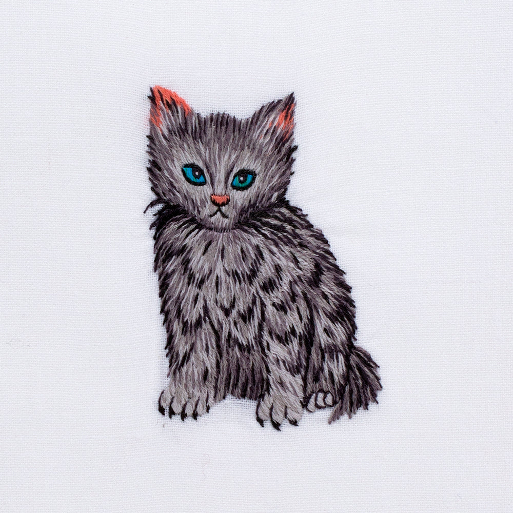 A detailed image of the embroidery - A sitting black & gray kitten with blue eyes