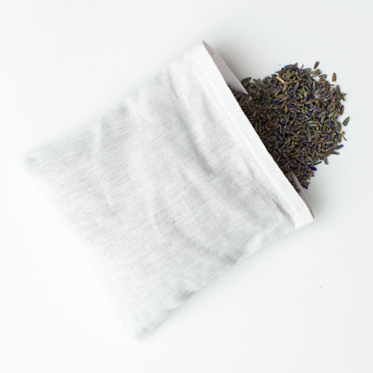 A white linen pouch filled with lavender spilling out the open side