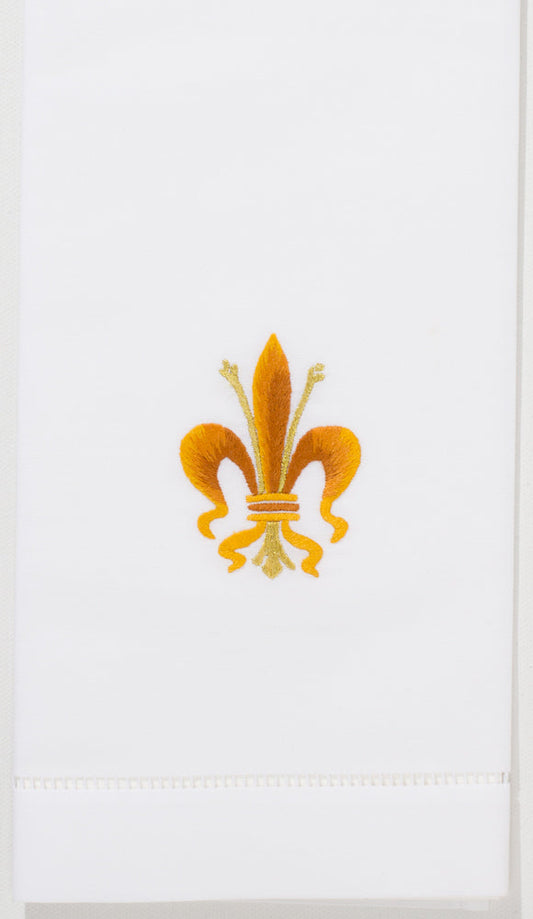 A white hand towel with a hemstitch. A yellow & gold fleur-de-lis symbol is embroidered in the center