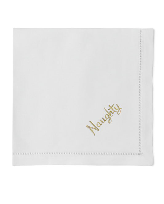 A white napkin with a hemstitch. The word “naughty” in gold is embroidered in the bottom right corner