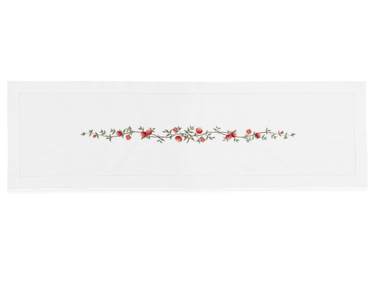 A white table runner with a hemstitch border. A branch of pomegranates extends down a line in the middle.