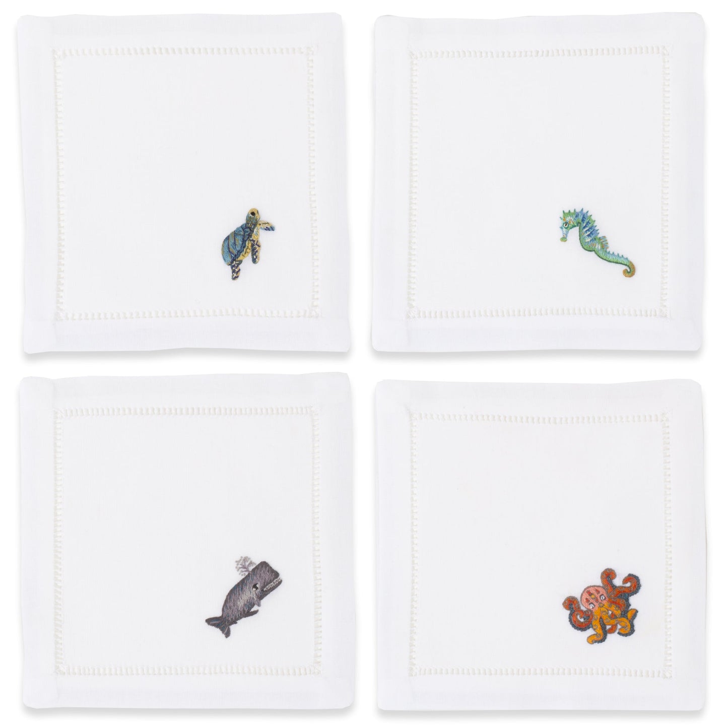 4 white cocktail napkins with a hemstitch border. Embroidered on the bottom right corner of each is a whale, seahorse, octopus, and turtle