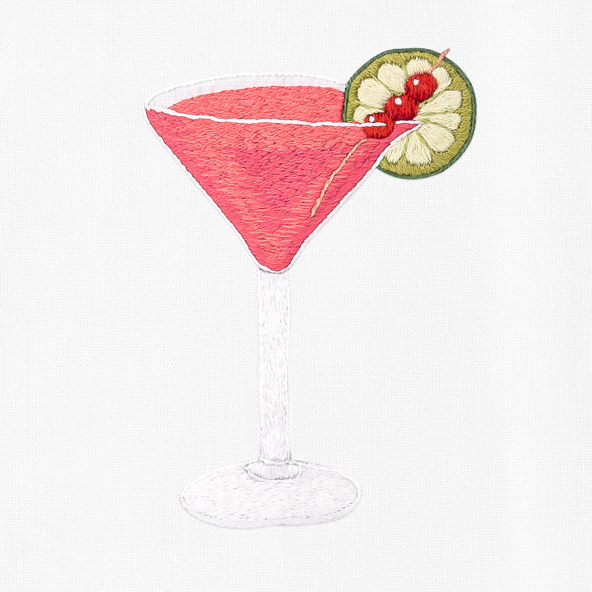 an embroidered cosmopolitan cocktail with a lime slice and cherries