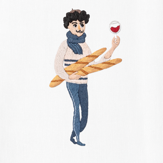 A close up detailed image of the embroidery - A man in blue and white holding 2 baguettes and a glass of red wine