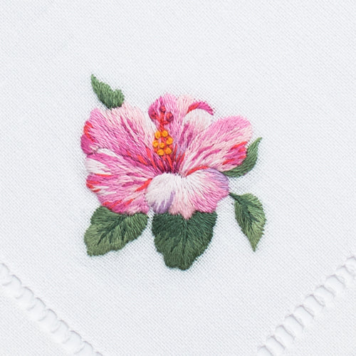 an embroidered pink hibiscus flower with green leaves